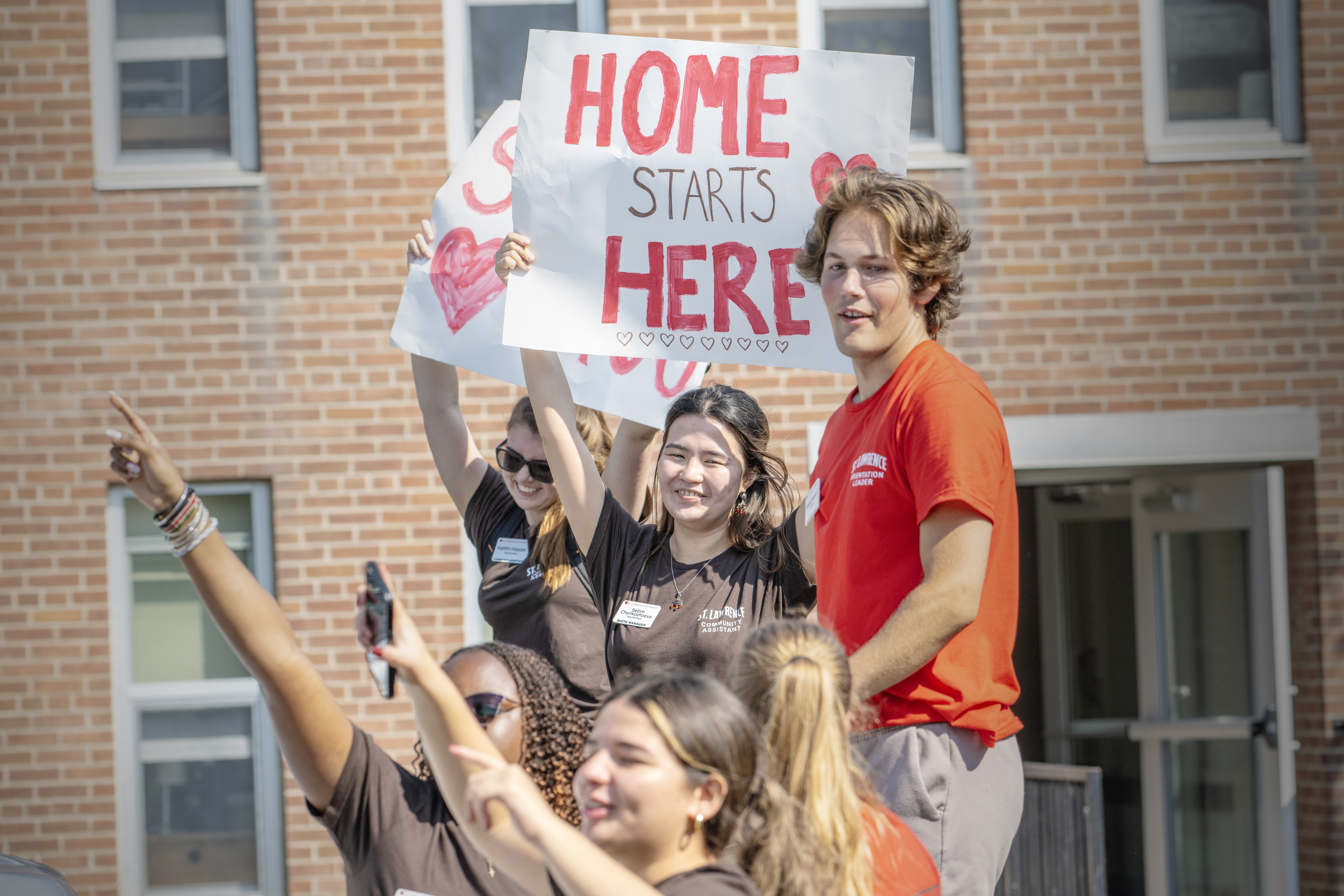 Students with a Sign that Reads Home Starts Here